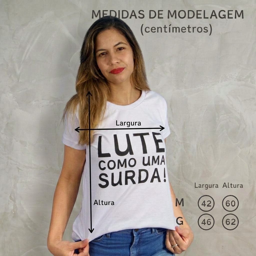 Letícia Lima vestindo camiseta branca com a frase "LUTE COMO UMA SURDA!" em letras pretas. A imagem mostra as medidas da modelagem em centímetros: largura e altura da camiseta, com tamanho M 42x60 e tamanho G 46x62, sobre fundo cinza claro.
